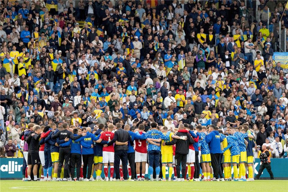 Nach dem Zusammenbruch von Christian Eriksen versammeln sich dänische und ukrainische Spieler gemeinsam auf dem Spielfeld.Bo Amstrup/Ritzau Scanpix Foto/AP/dpa