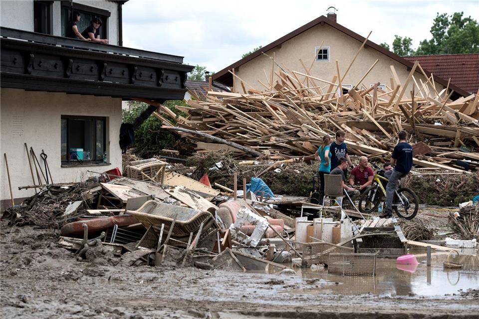 Nach der Flut im Juni 2016 sitzen Anwohner in der Innenstadt von Simbach am Inn zwischen Schlamm und Unrat auf der Straße. (Archivbild)Sven Hoppe/dpa