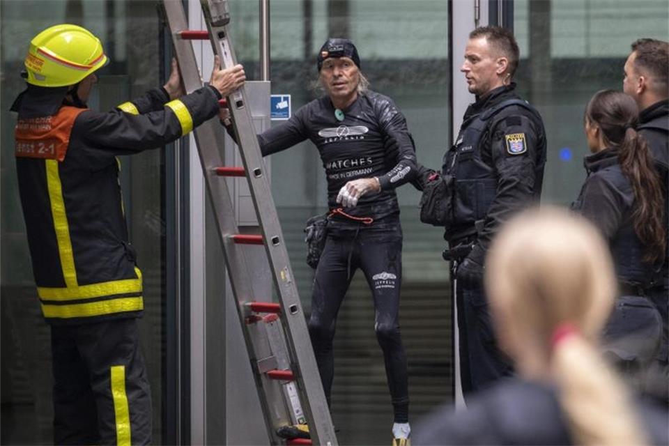 Hangelpartie in schwindelerregenden Höhe Nachdem er die Fassade des Skyper-Hochhauses wieder hinunter geklettert war, wird der Extremkletterer von Polizisten in Empfang genommen. Foto: Boris Roessler