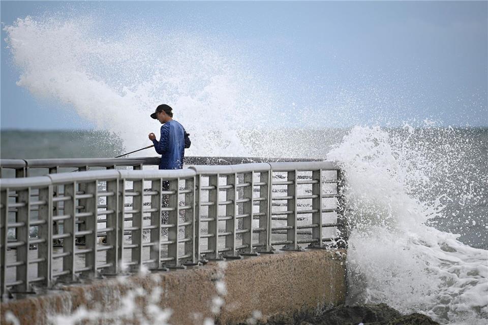Nathan Goff wird beim Angeln auf dem Steg im Sebastian Inlet State Park von einer Welle durchnässt, als der Tropensturm Imelda in Melbourne Beach, Florida, an der Küste vorbeizieht.Phelan M. Ebenhack/FR121174 AP/AP/dpa