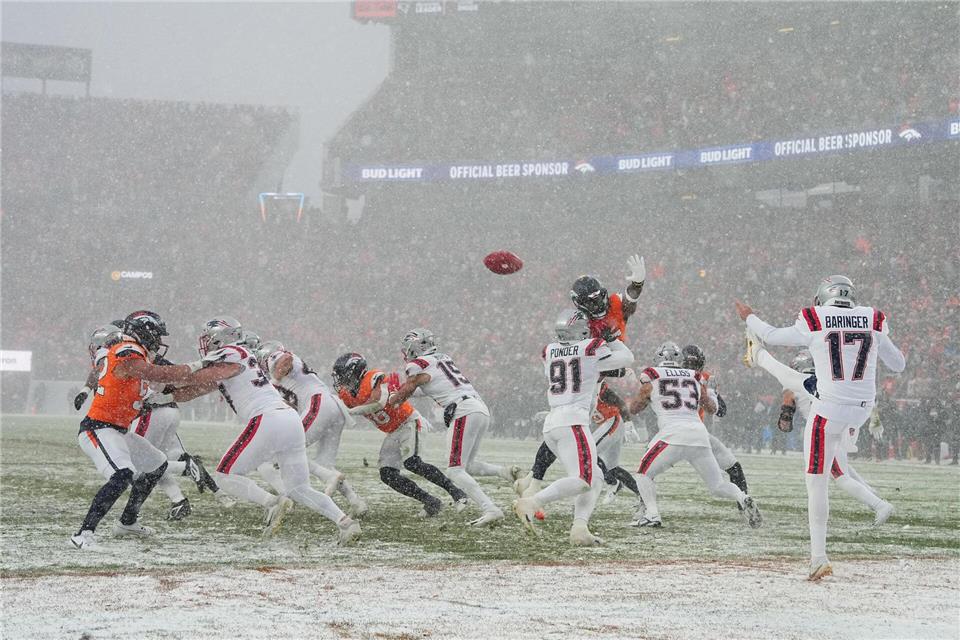 New England Patriots Punter Bryce Baringer (M) bei Schneefall in Aktion.Garrett W. Ellwood/AP/dpa