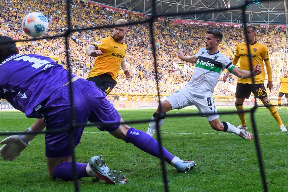 Nils Fröling (Dynamo Dresden, 2.v.l) erzielt gegen Torwart Nahuel Noll (Hannover 96) und Enzo Leopold (Hannover 96) das Tor zum 2:1.Robert Michael/dpa