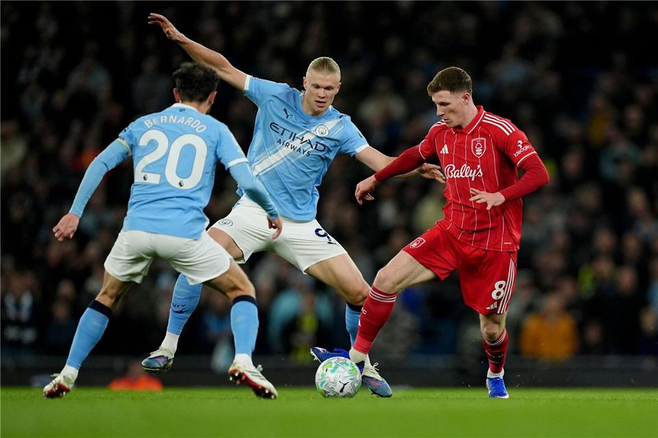 Nottinghams Torschütze Elliot Anderson (r) im Zweikampf mit Erling Haaland (M) und Bernardo Silva.Martin Rickett/PA Wire/dpa