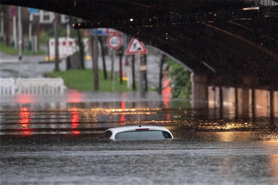 Nur das Dach eines Autos schaut noch aus dem Wasser, das eine Bahnunterführung geflutet hat. Foto: Marius Becker/dpa