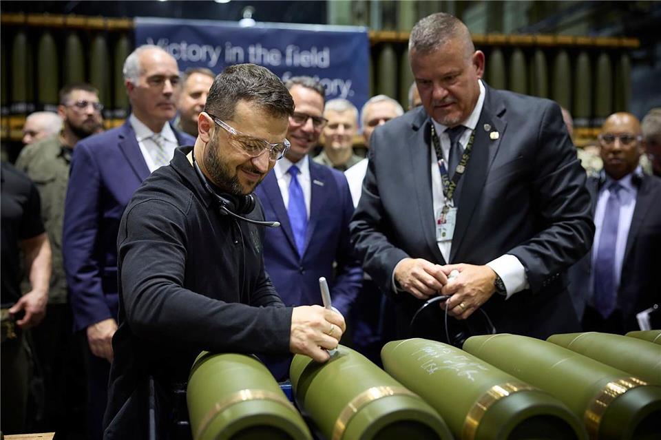Ob er „Grüße nach Moskau“ auf die Artilleriegranaten schreibt? Der ukrainische Präsident Wolodymyr Selenskyj hat eine Munitionsfabrik in den USA besucht.-/Office of the Ukrainian Presidency via AP/dpa