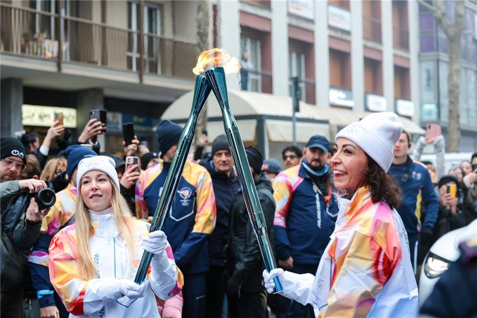 Olympische Winterspiele: Athletinnen beim Fackellauf mit der Flamme in Cortina D’ampezzo.Luciano Maria Bisi/LiveMedia-IPA/ZUMA Press Wire/dpa