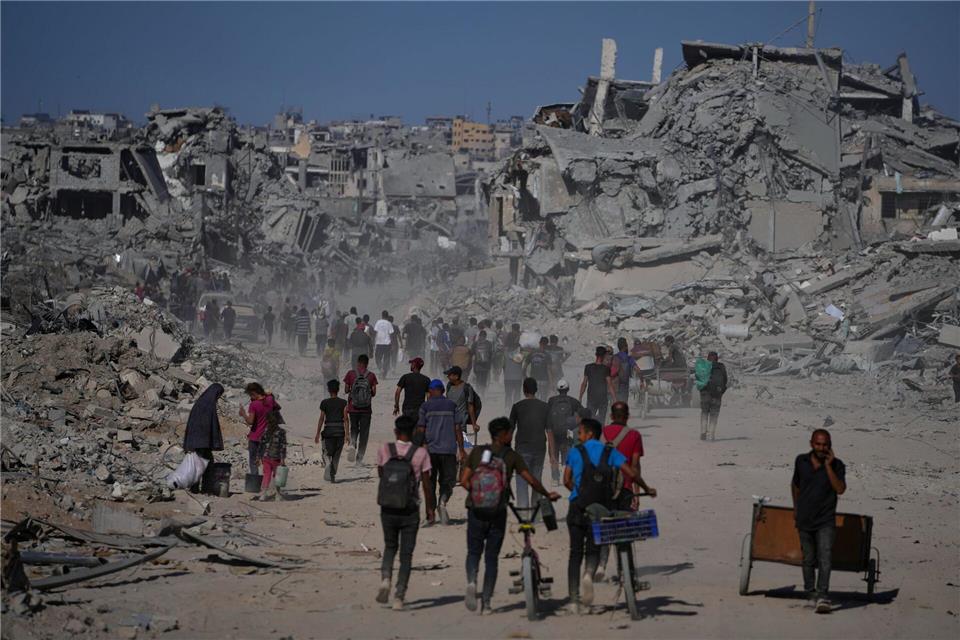 Bilder des Tages Palästinenser gehen an zerstörten Gebäuden vorbei, während sie in ihre Häuser im Zeitoun-Viertel von Gaza zurückkehren.Jehad Alshrafi/AP/dpa