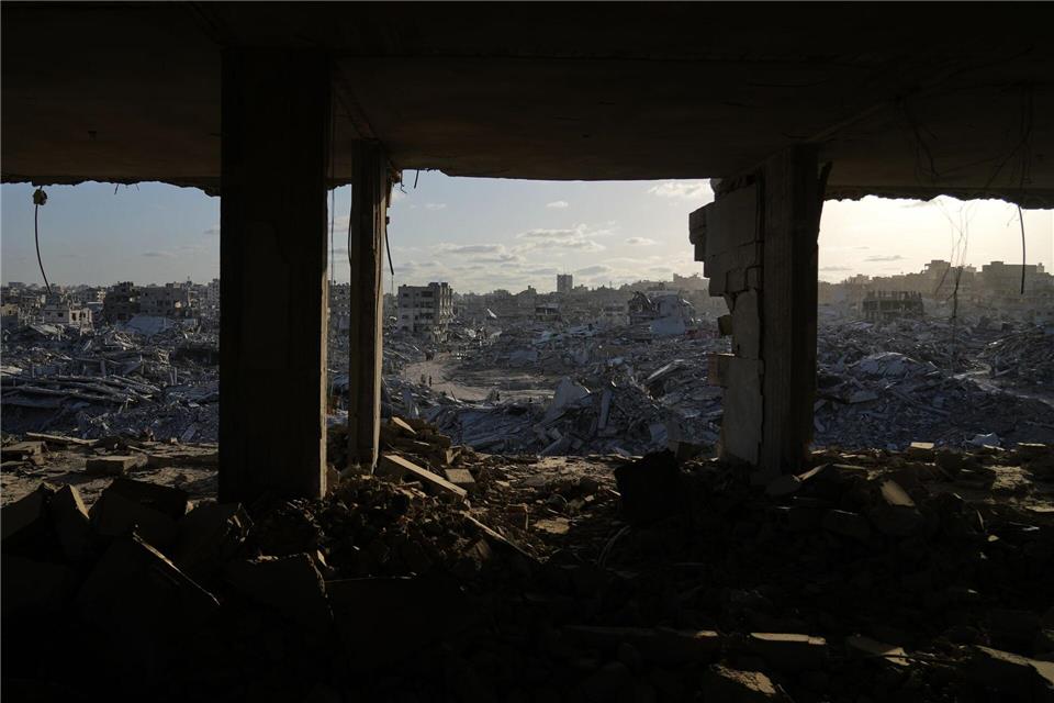 Palästinenser gehen zwischen den Trümmern der Stadt Gaza.Abdel Kareem Hana/AP/dpa