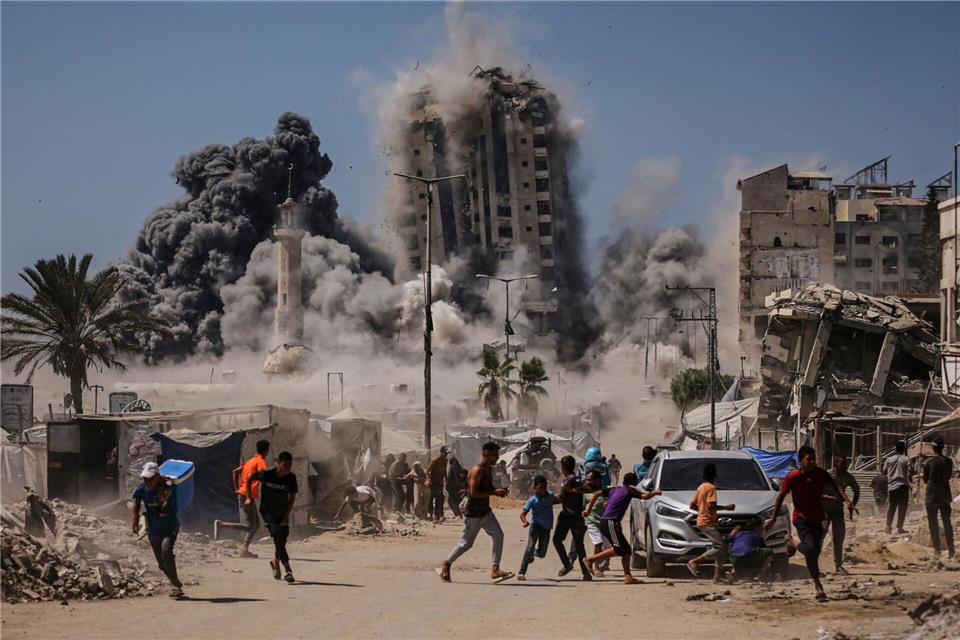 Bilder des Tages Palästinenser suchen während eines israelischen Luftangriffs auf ein Hochhaus im Gaza Schutz, nachdem die israelische Armee zuvor eine Warnung herausgegeben hatte.Yousef Al Zanoun/AP/dpa