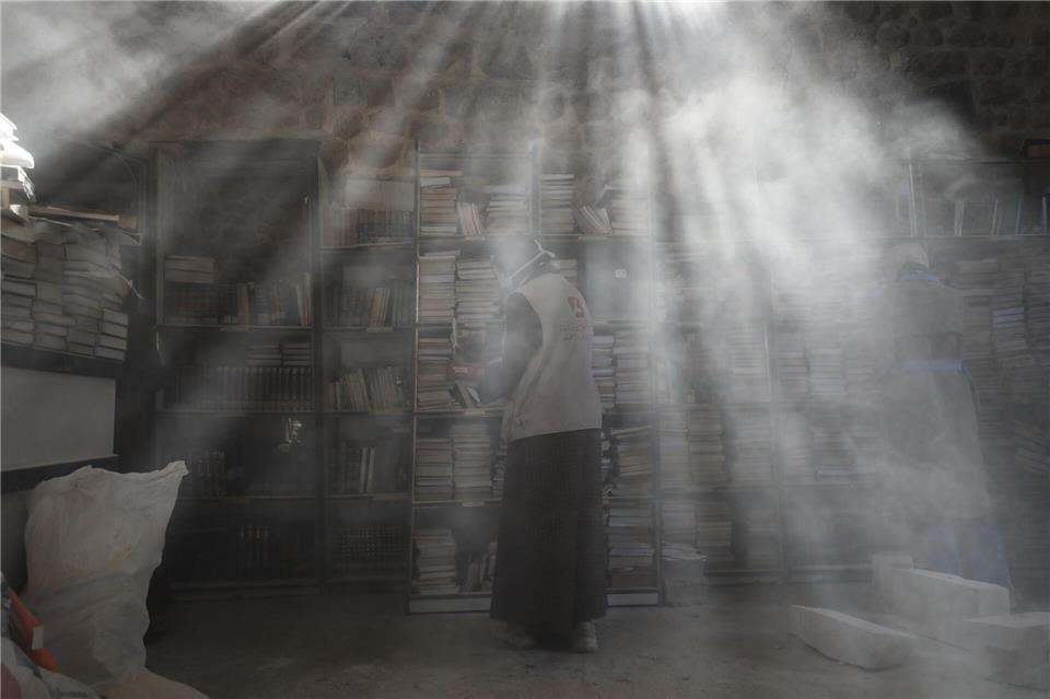 Palästinensische Freiwillige entstauben in der Bibliothek der Großen Omari-Moschee in der Altstadt von Gaza-Stadt Bücher, um beschädigte Bestände nach der zweijährigen Bombardierung des Gazastreifens zu retten und zu restaurieren.Omar Ashtawy/APA Images via ZUMA Press Wire/dpa