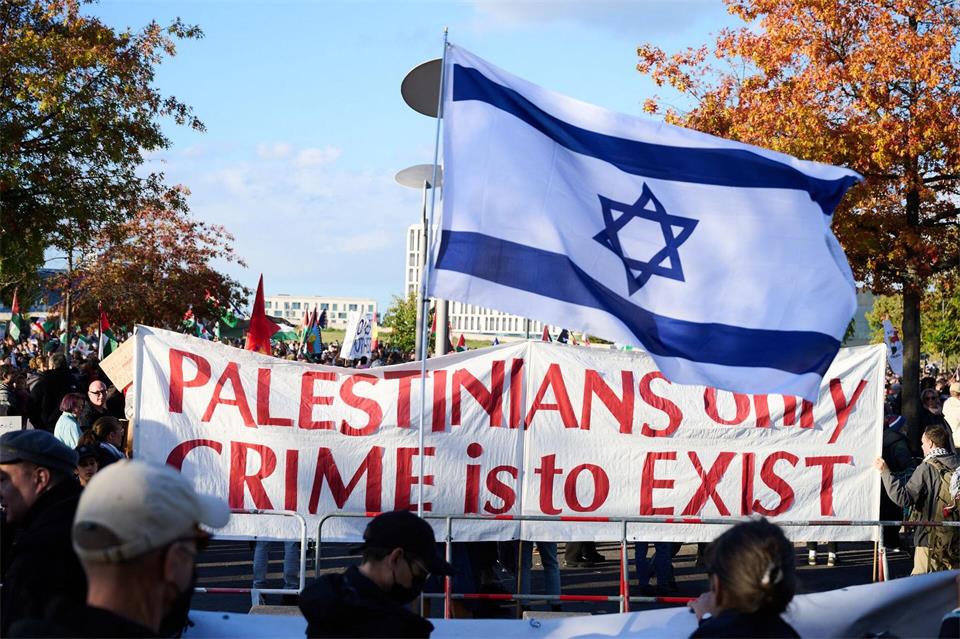 „Palestinians only crime is to Exist“ steht auf einem Transparent, das propalästinensischen Demonstranten halten, während ein Gegendemonstrant eine Flagge mit Davidsstern schwingt.Annette Riedl/dpa
