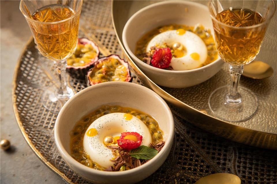 Panna Cotta mit Passionsfrucht, Himbeere, Mangotupfer, Minze, Pistazie, Schokolade und goldenen Schokokugeln in Savarin-Form zubereitet. Das ist eine Backform in flacher, ringförmiger Gestalt.  Christin Klose/dpa-tmn