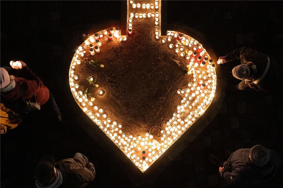 Passanten entzünden auf dem Neumarkt Kerzen am 81. Jahrestag der Zerstörung Dresdens.Sebastian Kahnert/dpa