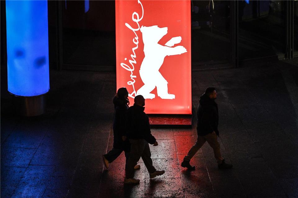 Passanten gehen am Abend der Preisverleihung an einem Berlinale-Plakat vorbei. Britta Pedersen/dpa