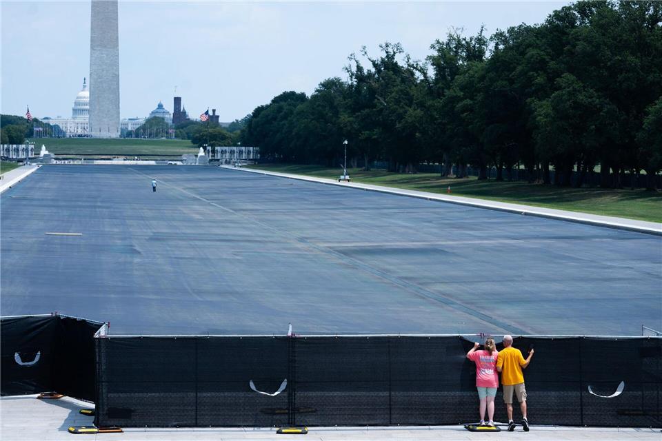 Passanten spähen in Washington über den Zaun.Allison Robbert/AP/dpa