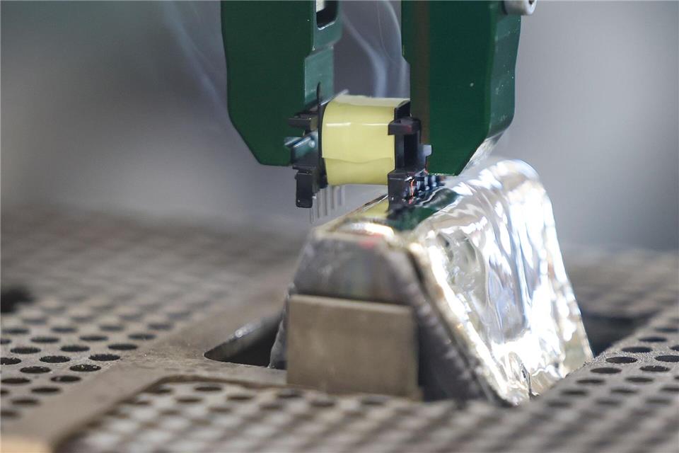 Per Roboter-Greifarm werden die Pins einer Spule in ein 400 Grad heißes Zinnbad getaucht.Jan Woitas/dpa