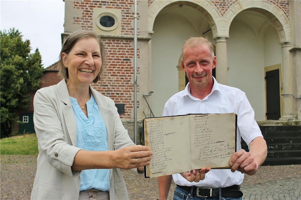 Petra Küppers übergibt das historische Buch der Schlossfreiheit stellvertretend für ihren Mann an Stefan Becker, den neuen Bürgermeister in der Freiheit.