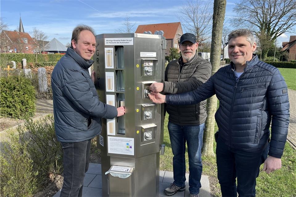 Pfarrer Dr. Fabian Tilling, Heinz Nienhaus und Klaus Bleker vom Kirchenvorstand testen den neuen Grablicht-Automaten auf dem Raesfelder Friedhof.