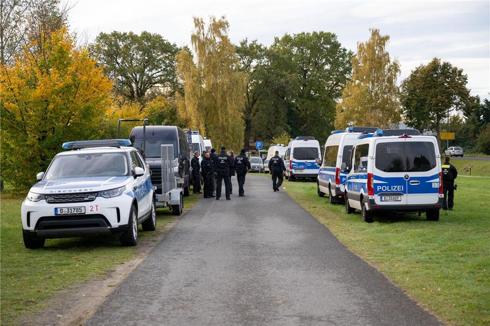 Polizeiautos stehen auf einer Wiese in Tauche. Christophe Gateau/dpa