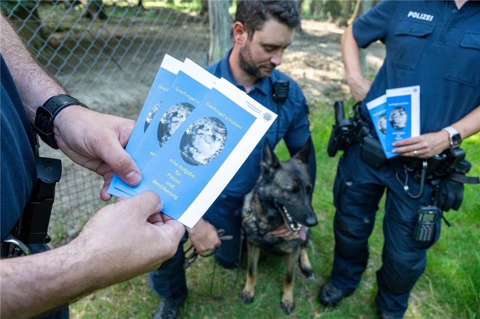 Polizeibeamte informieren Spaziergänger  in einem Wald mit Infomaterial über Maßnahmen gegen Straftaten an Wildtieren.Armin Weigel/dpa
