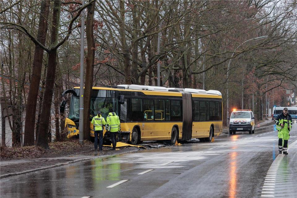 Polizisten stehen an einer Unfallstelle vor einem beschädigten Bus.Carsten Koall/dpa