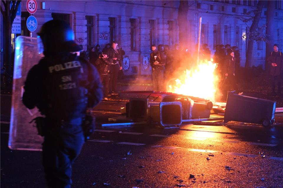 Demonstranten zünden im Leipziger Osten Barrikade an Polizisten stehen auf der Eisenbahnstraße in Leipzig vor brennenden Gegenständen.Sebastian Willnow/dpa