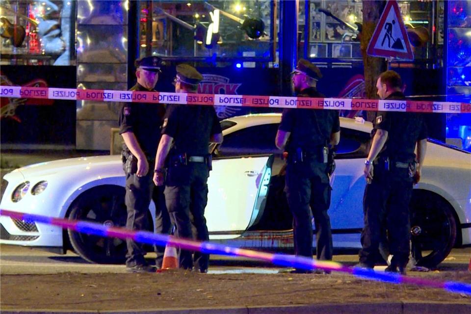 Nach Schüssen auf Rockerboss - zwei Helferinnen verurteilt Polizisten stehen im August 2018 neben dem Bentley des angeschossenen Rockers. (Archivbild)M�cahid G�ler/dpa