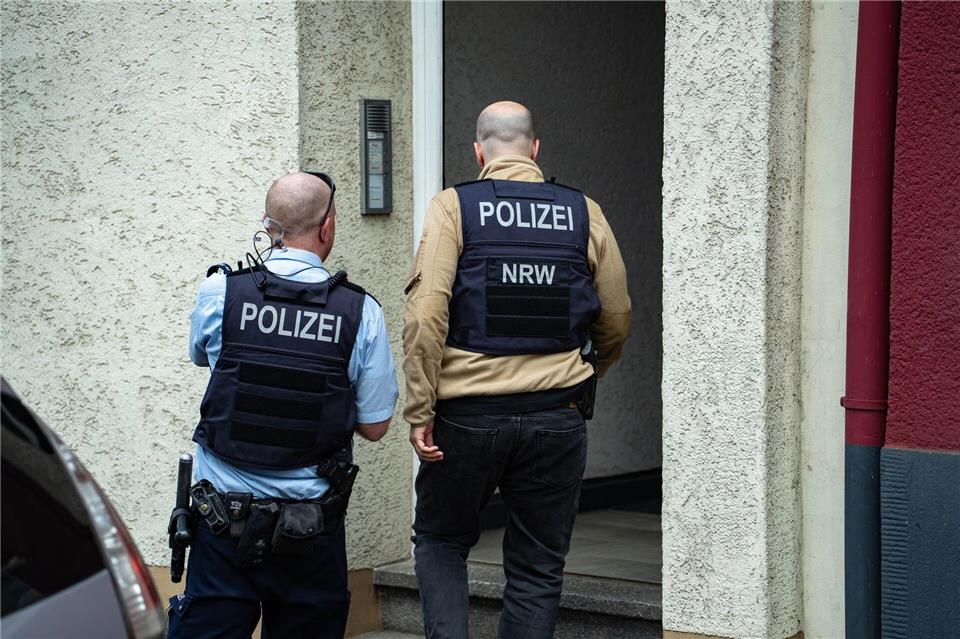 Polizisten stehen vor einem Hauseingang. Ein mutmaßlich der „Reichsbürger“-Szene angehörender Mann ist in Wuppertal von der Polizei festgenommen worden. (Symbolbild)-/Blaulicht-Solingen/dpa