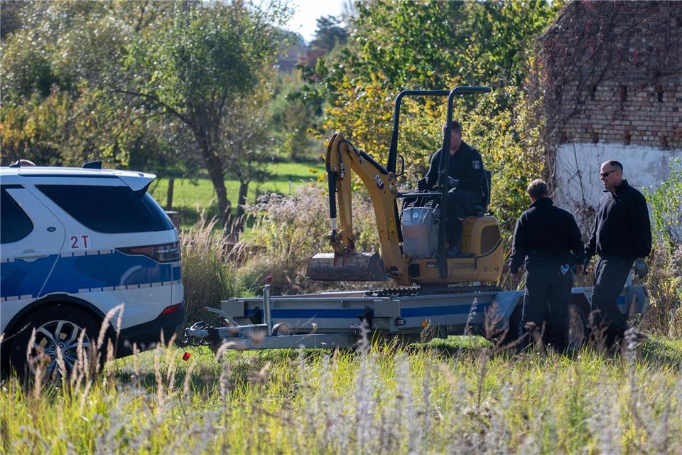 Polizisten untersuchen mit einem Bagger ein Grundstück in Herzberg (Landkreis Oder-Spree).Christophe Gateau/dpa