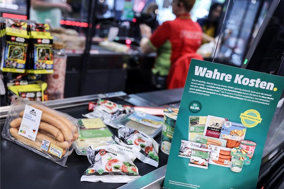 Pennys „Wahre Kosten“: Verkäufe weniger stark gesunken Produkte, deren Preis mit den verdeckte Kosten angepasst wurden, liegen auf einem Kassenband.
