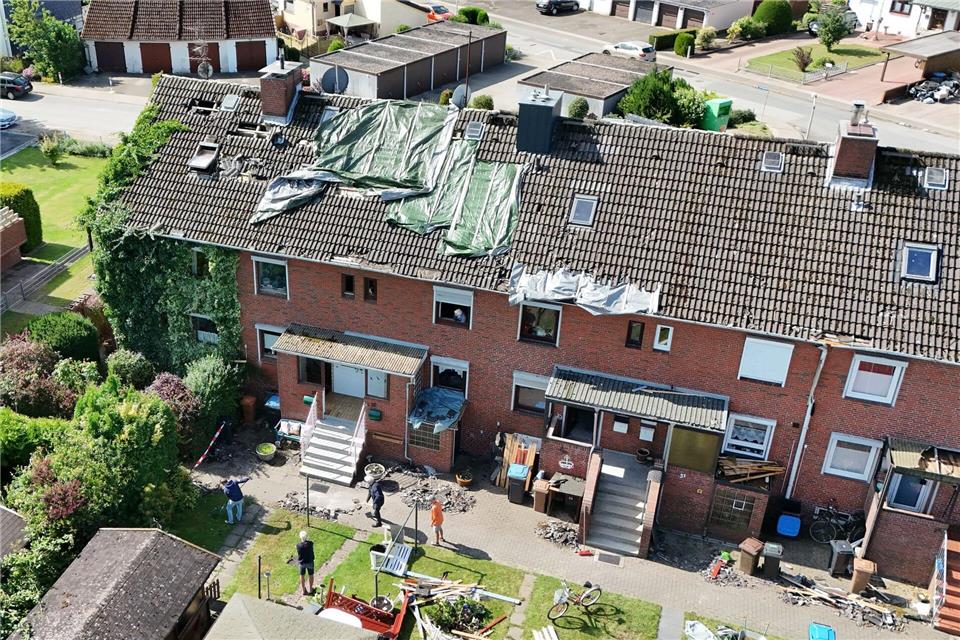 Provisorische Planen bedecken das durch ein Unwetter abgedeckte Dach eines Reihenhauses in Glückstadt (Aufnahme mit einer Drohne). Marcus Brandt/dpa