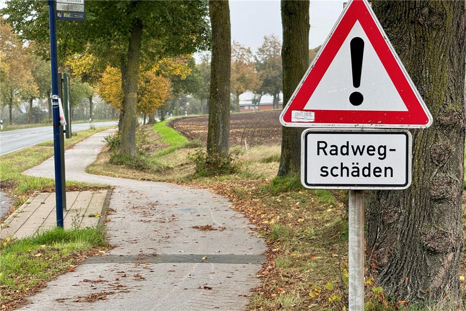 Radfahrer werden per Schild gewarnt (hier in Höhe der Haltestelle Bösweg). Unter anderem die Wurzeln der Bäume am Wegesrand haben dafür gesorgt, dass der Radweg eine Wellenstrecke ist.