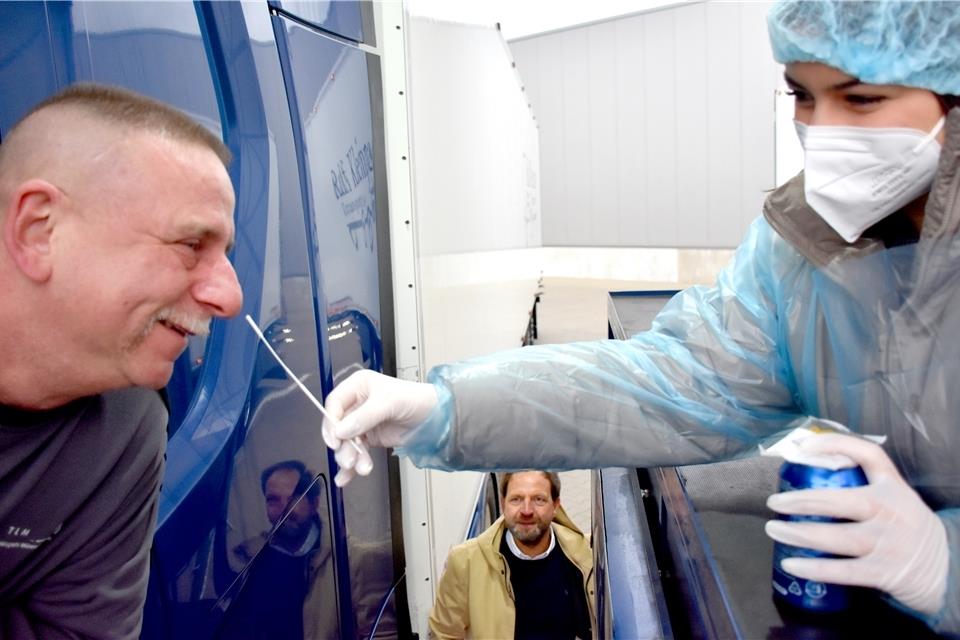 Ralf Kleinpas (Mitte, 48) hat seine Spedition vor 22 Jahren mit einem Lkw gegründet. Derzeit sind auf das Unternehmen 44 Sattelschlepper angemeldet. 55 Fahrer sind mit ihnen unterwegs. In der Teststelle auf dem Betriebshof kommen die Tester über eine Brücke an die Fahrerfenster heran.