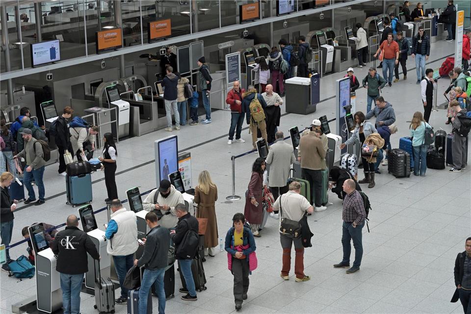 Reisegäste stehen an Check-In-Schaltern am Flughafen.Malin Wunderlich/dpa