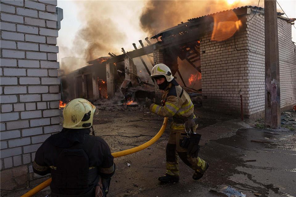 Rettungskräfte löschen ein Feuer in einer Kiewer Autowerkstatt, die durch einen russischen Angriff beschädigt wurde.Evgeniy Maloletka/AP/dpa