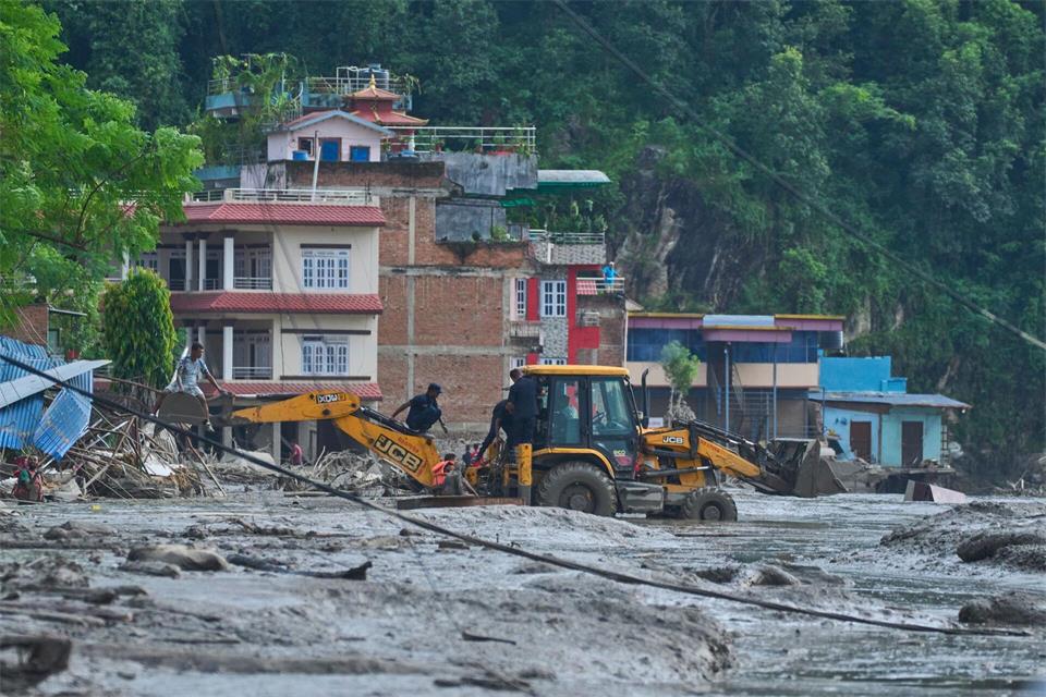 Rettungskräfte setzen Baumaschinen ein, um unter Wasser stehende Häuser nach Sturzfluten zu erreichen.Niranjan Shrestha/AP/dpa