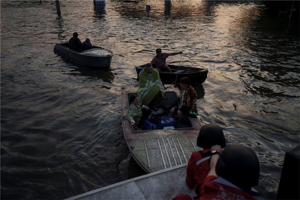 Rettungskräfte versuchen, Boote mit Bewohnern abzuschleppen.