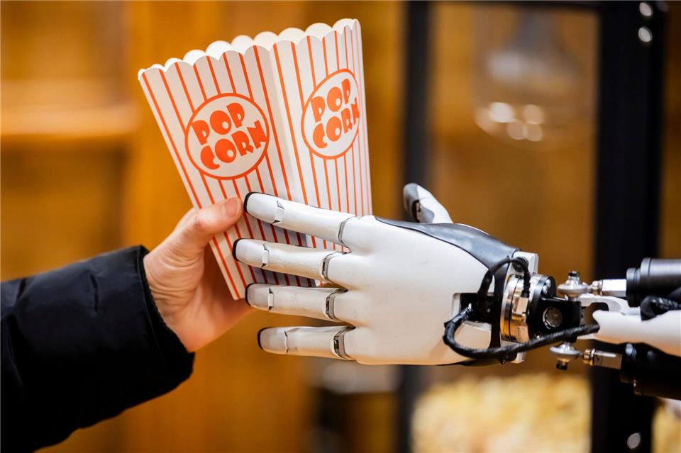 Roboter „Optimus“ griff kleine Popcorn-Boxen, füllte sie auf und überreichte sie den Besuchern.Christoph Soeder/dpa