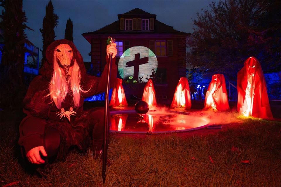 Rot gewandete Wächter, ohne Gesicht und Körper, vollziehen an einem nebelumhüllten Teich ein Ritual.Boris Roessler/dpa
