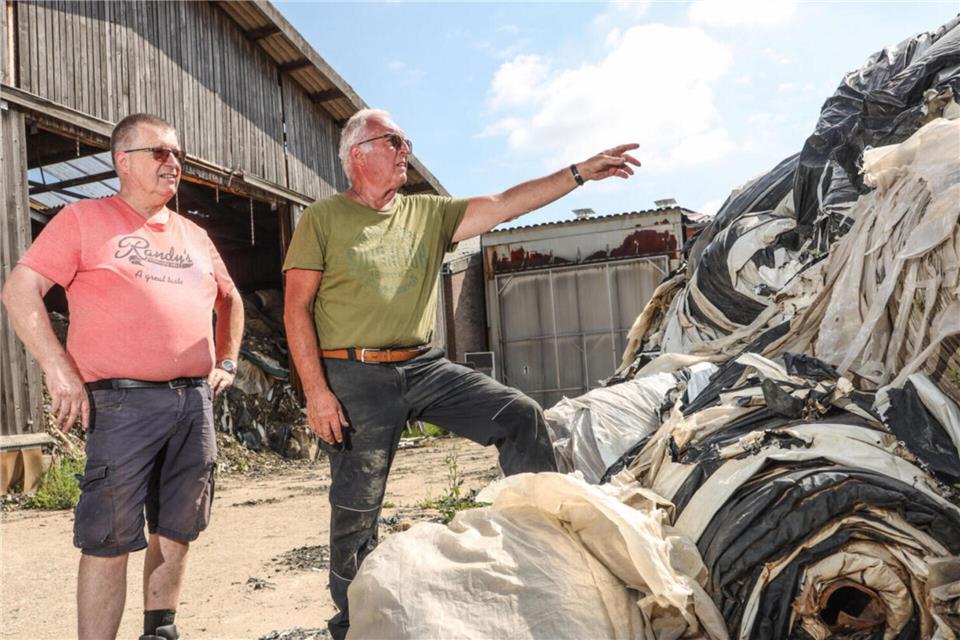 Roy (links) und Dietmar Kemink stehen vor dem meterhohen Abfallhaufen auf dem Gelände ihres Sägewerks in Suderwick. Wie der Müll dort wieder verschwinden soll, wissen sie nicht.