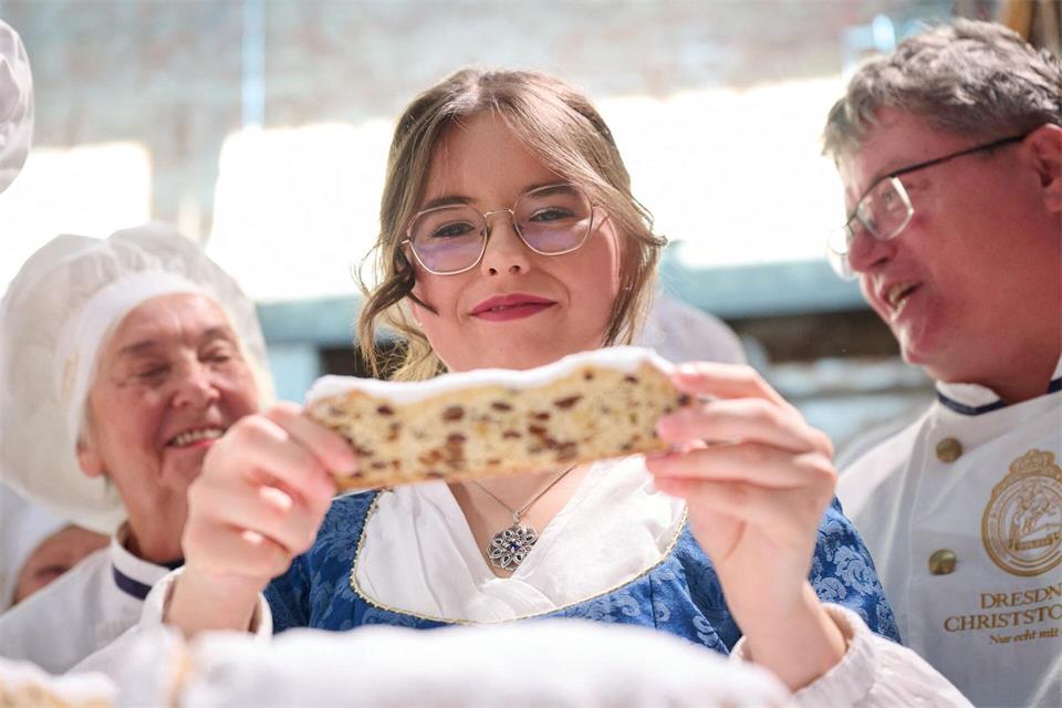 Ruth Liebscher hält die erste Scheibe aus dem von ihr angeschnittenen Stollen in der Hand.Katharina Kausche/dpa