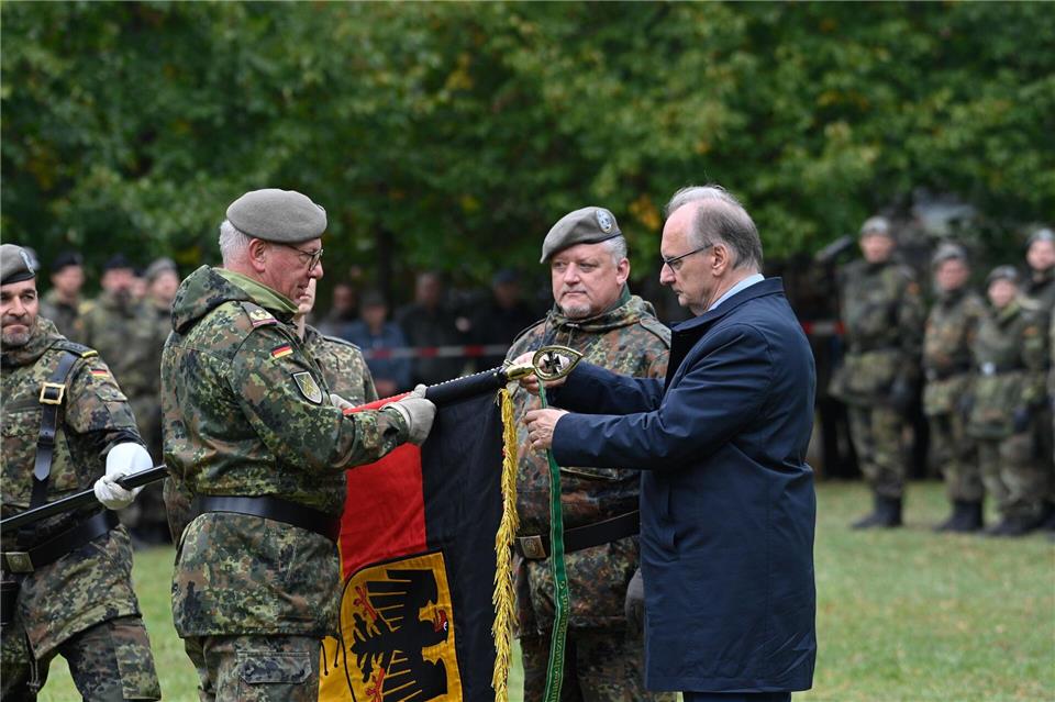 Sachsen-Anhalts Ministerpräsident Reiner Haseloff befestigte an der Fahne das Band mit dem Namen des Regiments.Klaus-Dietmar Gabbert/dpa