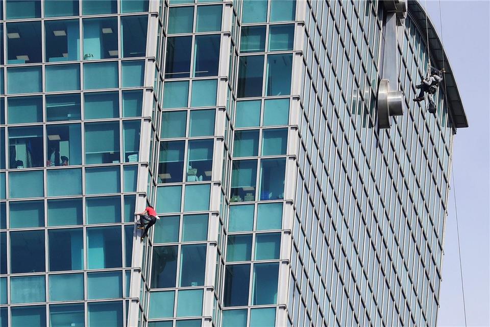 Schaulustige beobachteten Alex Honnold nicht nur vom Boden aus - auch hinter den Bürofenstern wurde der Extremsportler angefeuert.ChiangYing-ying/AP/dpa