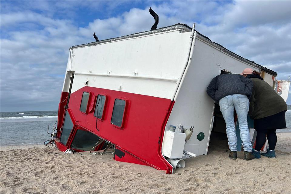 Schaulustige schauen sich auf Sylt einen angespülten Bootsaufbau an.Lea Albert/dpa