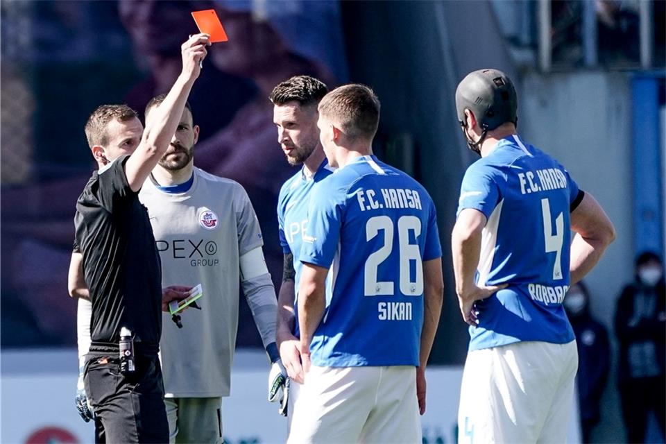 Schiedsrichter Robin Braun (l) zeigt Rostocks Danylo Sikan (2.v.r.) nach einer Tätlichkeit die Rote Karte.