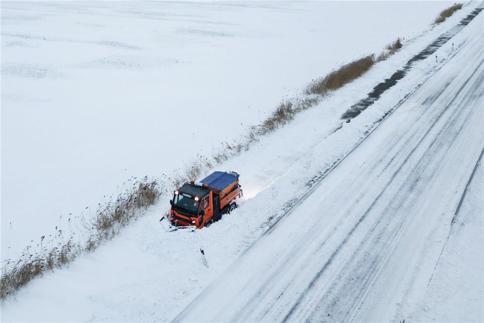 Schneepflug kämpft gegen Verwehungen auf Gehweg bei BingumLars Penning/dpa