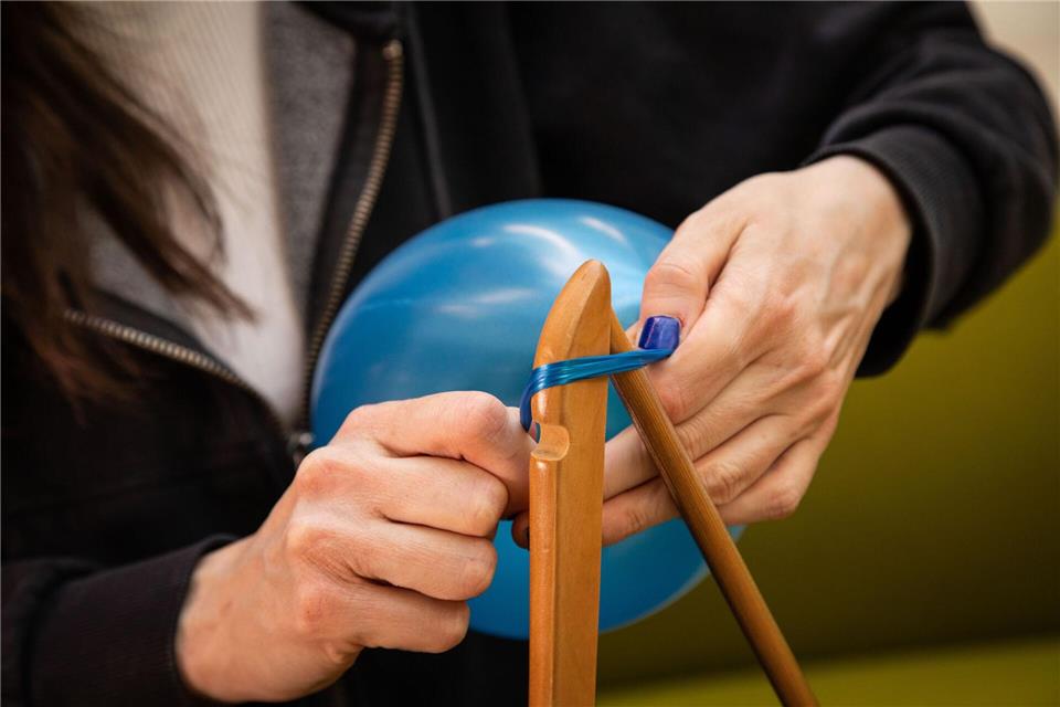 Schritt 1: Den Hals des Luftballons um ein Ende des Kleiderbügels wickeln.Christin Klose/dpa-tmn