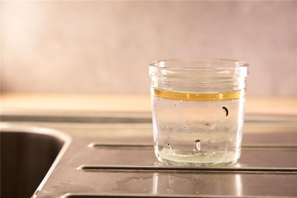 Schritt 1: Heißes Wasser in das Glas gießen und einige Minuten stehen lassen, bis das Wachs kalt geworden ist.Christin Klose/dpa-tmn