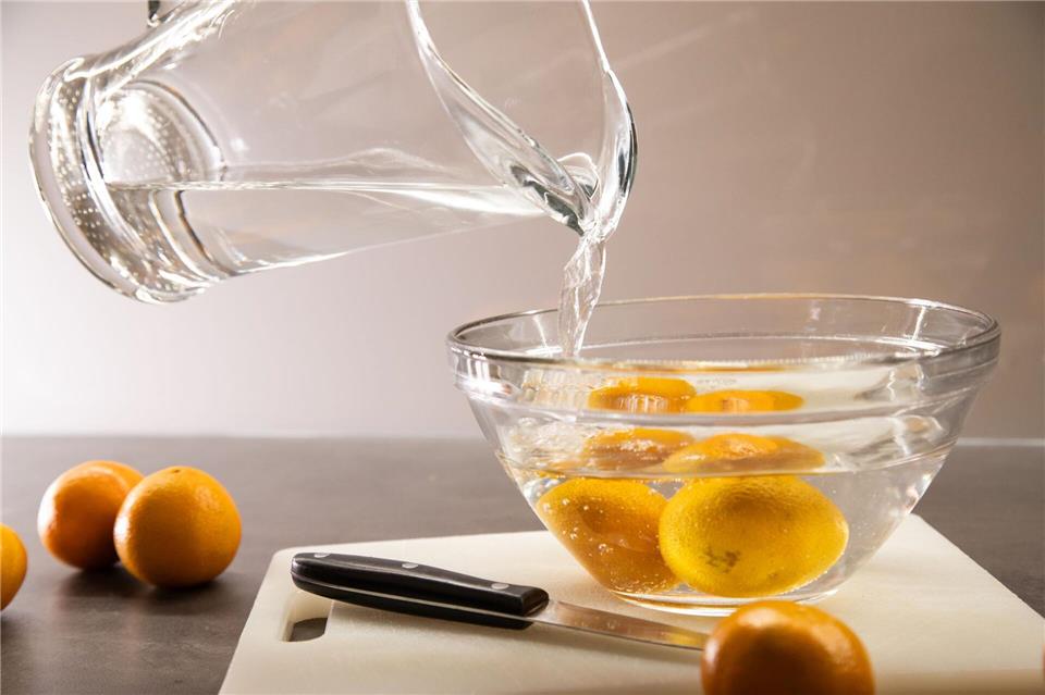 Schritt 1: Heißes Wasser über die Clementinen gießen und eine Minute ziehen lassen.Christin Klose/dpa-tmn