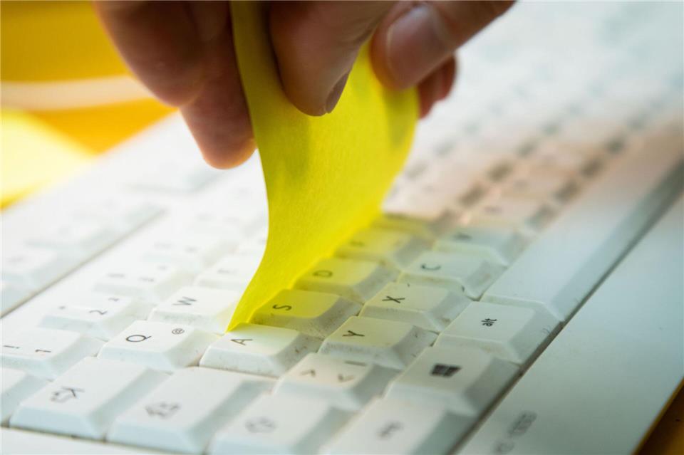 Tastatur reinigen mit einfachem Trick - so geht’s Schritt 2: Den Zettel zwischen die Tastenreihen schieben und durchziehen.Christin Klose/dpa-tmn